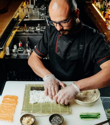 Chef skillfully prepares sushi with fresh ingredients at a restaurant.